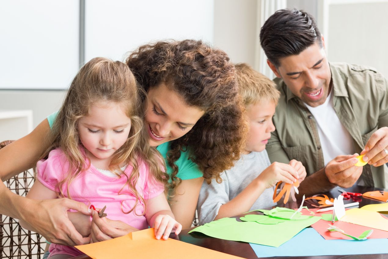 Familie beim gemeinsamen Basteln mit Papier – kreative Aktivitaet mit Kindern, die sich gut mit der Buttonmaschine erweitern laesst
