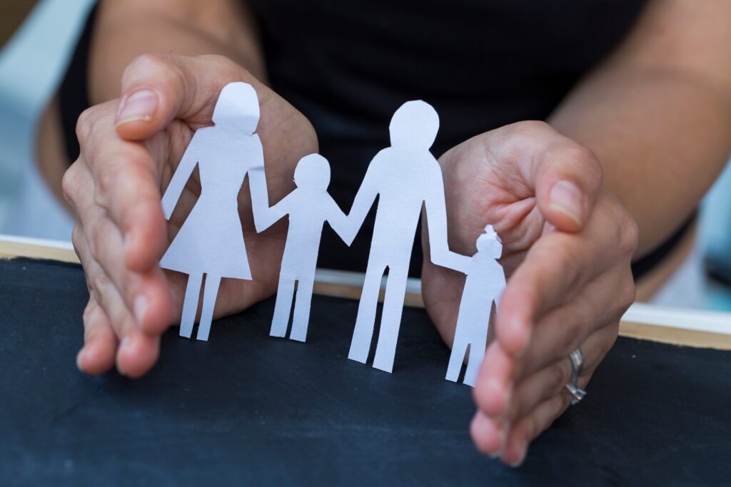 Hände schützen ausgeschnittene Papierfamilie | Geschenk zur Geburt