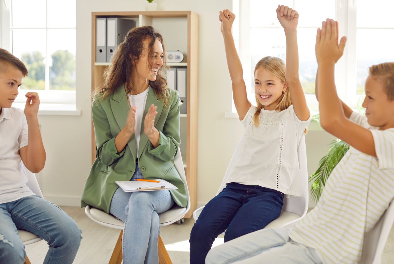kinder sitzen in einer gruppenrunde und freuen sich ueber einen gelungenen moment, als waere es eine medaille fuer ihren einsatz