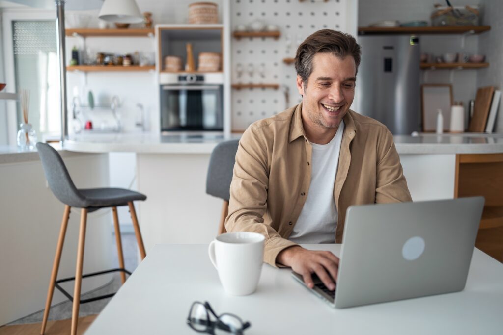 Mann arbeitet am Laptop in moderner Küche | Wasserspender für zuhause